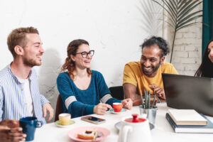 Group of students from different parts of the world having a brunch and studying in a cafeteria, young people having fun during a break in the morning